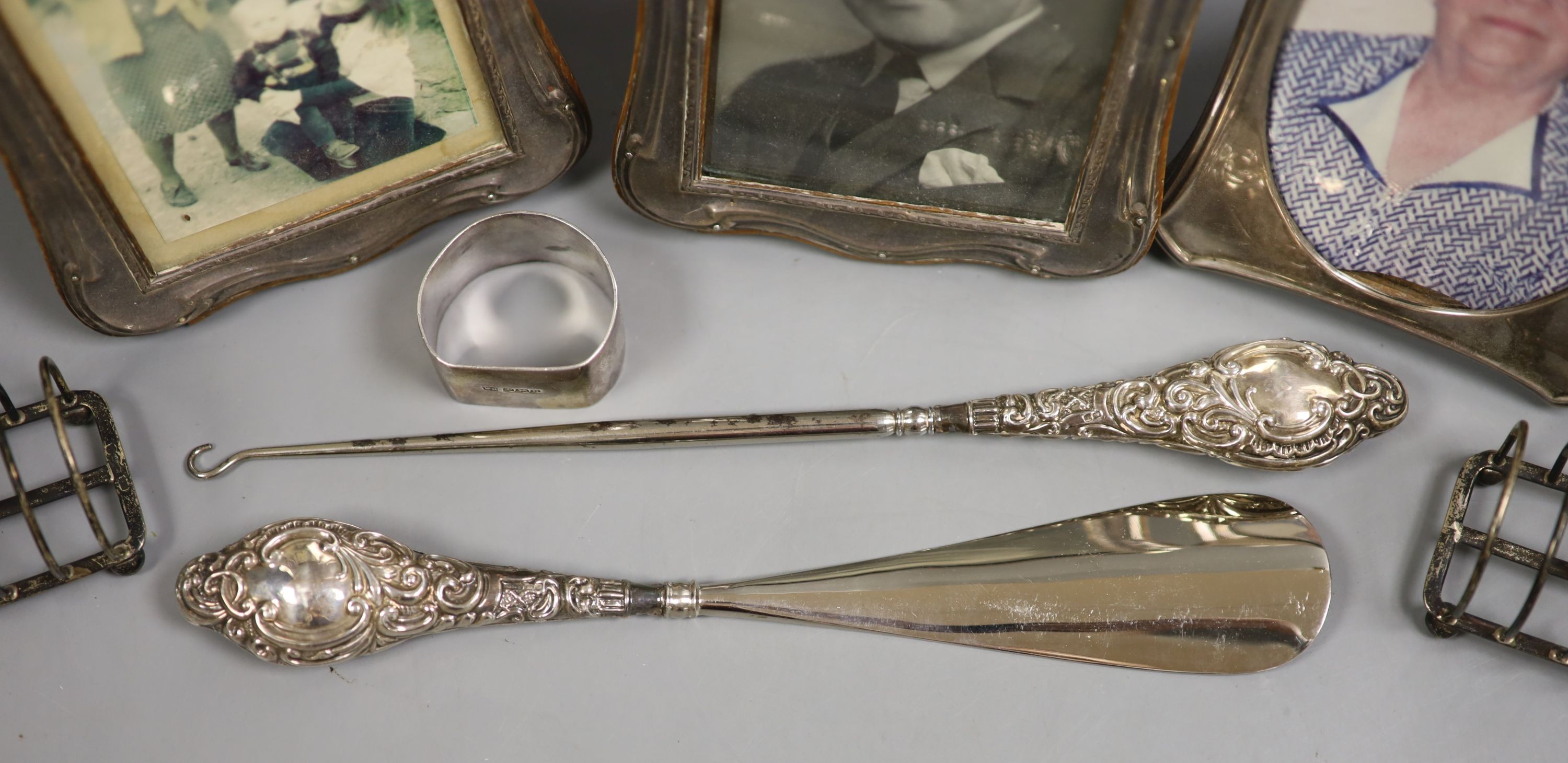 A pair of George V silver mounted photograph frames, Birmingham, 1915, 17.2cm, one other frame, a pair of small silver toast racks, a silver napkin ring, a silver mounted button hook and shoehorn.